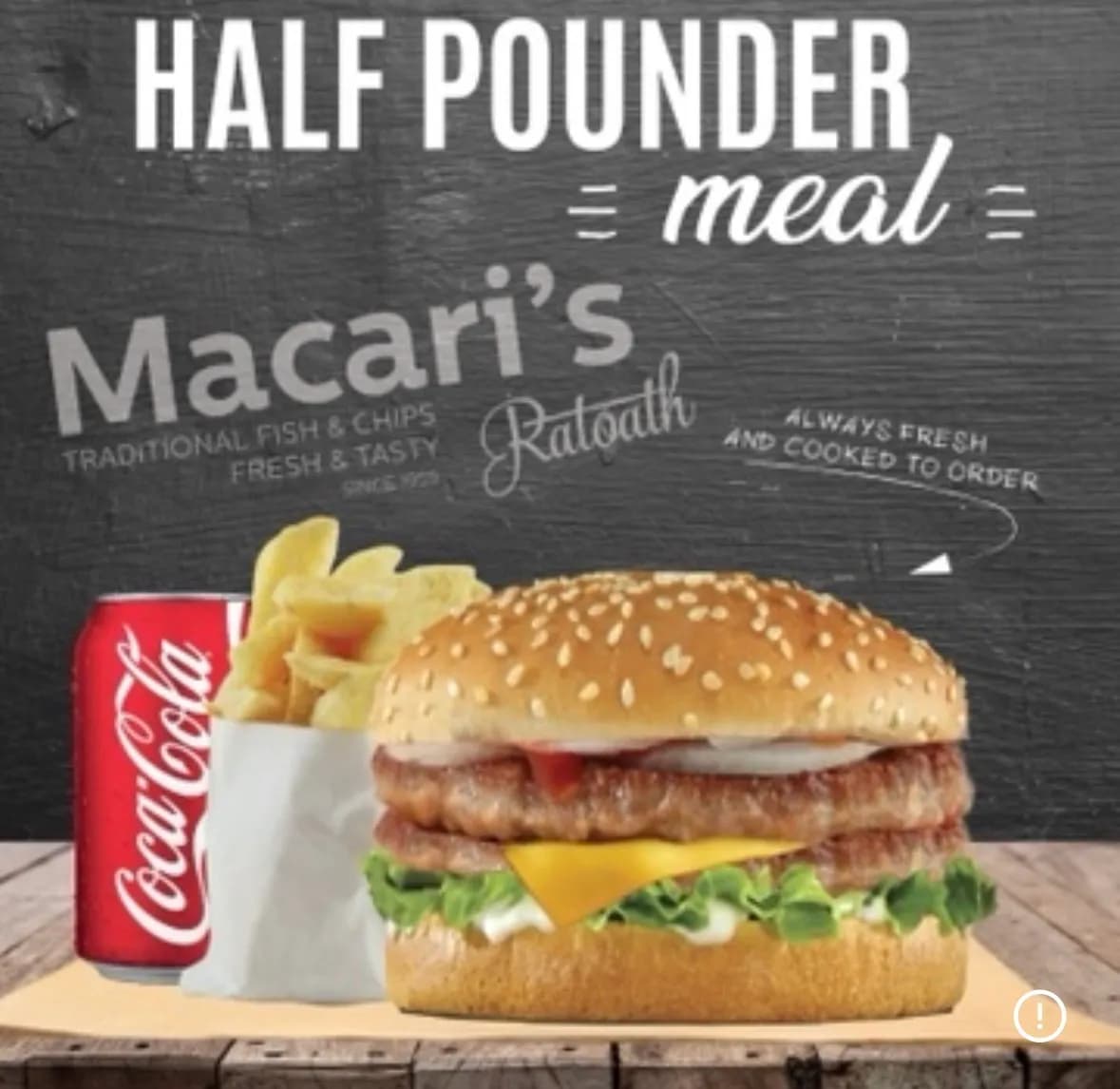 Half pounder burger meal with chips and a can of Coca-Cola, served on a wooden table with a dark chalkboard-style background.