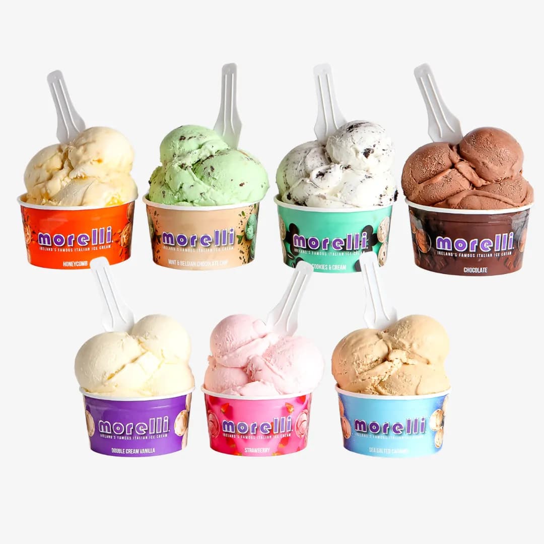 Selection of Morelli ice cream tubs in different flavours, including chocolate, strawberry, cookies & cream, mint chocolate chip, vanilla, and caramel, each topped with scoops and served with small spoons against a clean background.
