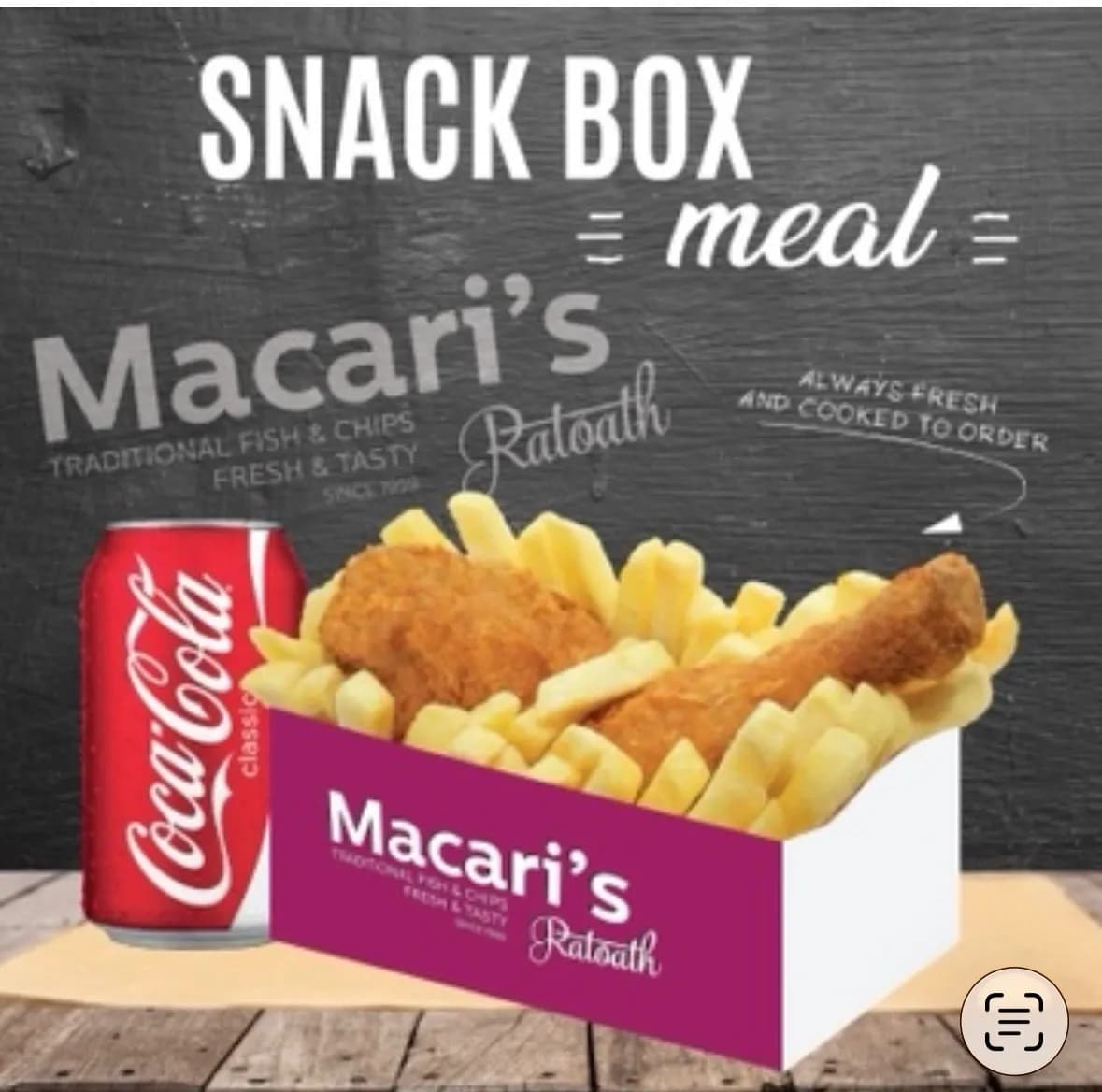 Snack box meal with chicken pieces, chips and a can of Coca-Cola, served in a takeaway box on a wooden table with a dark chalkboard-style background.