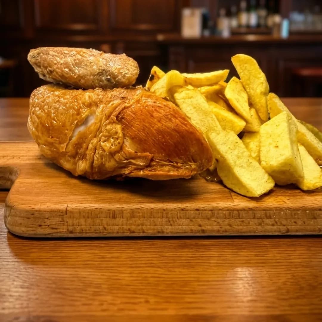 Roast chicken breast served with thick-cut chips on a wooden board.